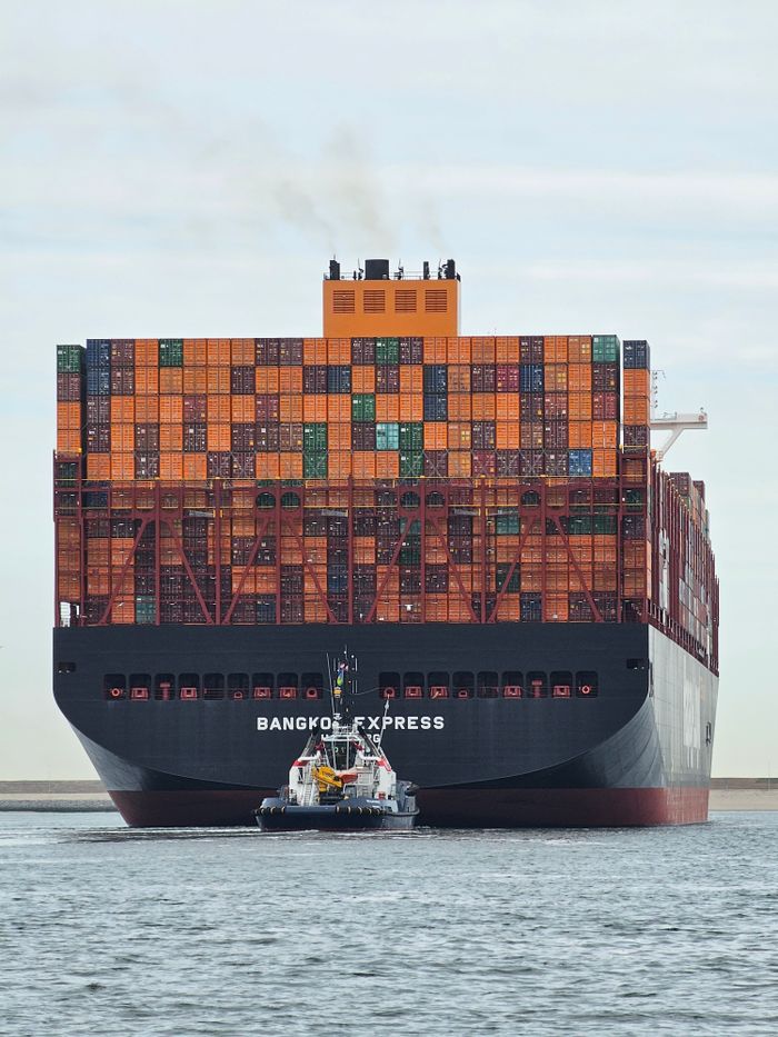 Large container ship Bangkok Express with tugboat at Maasvlakte Rotterdam.